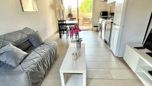 A modern living room with a grey sofa, a white coffee table, and a dining area with a table and chairs. - T2 apartment, 40 m2, fully air-conditioned, 350 m from the beach. Private parking (Saint Cyr sur Mer)