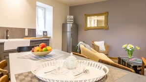 A modern kitchen with a dining area, a refrigerator, and a mirror on the wall. - Le P'tit Pichot Charming Cottage in little wine village 8kms from Beaune (Nantoux)