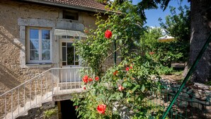 A stone building with a balcony, a metal railing, and a rose bush. - Le P'tit Pichot Charming Cottage in little wine village 8kms from Beaune (Nantoux)