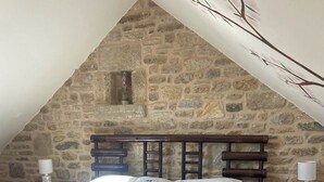 Een slaapkamer met een stenen muur, een houten bed en twee nachtkastjes met lampen.