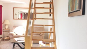 A wooden staircase with a view of a living room, including a sofa, a table, and a painting. - Peaceful retreat with garden, terrace, WiFi & private parking (3 guests) (Wailly-Beaucamp)