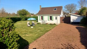 A house with a well-maintained lawn, a patio with two chairs and an umbrella, and a gravel driveway. - Peaceful retreat with garden, terrace, WiFi & private parking (3 guests) (Wailly-Beaucamp)