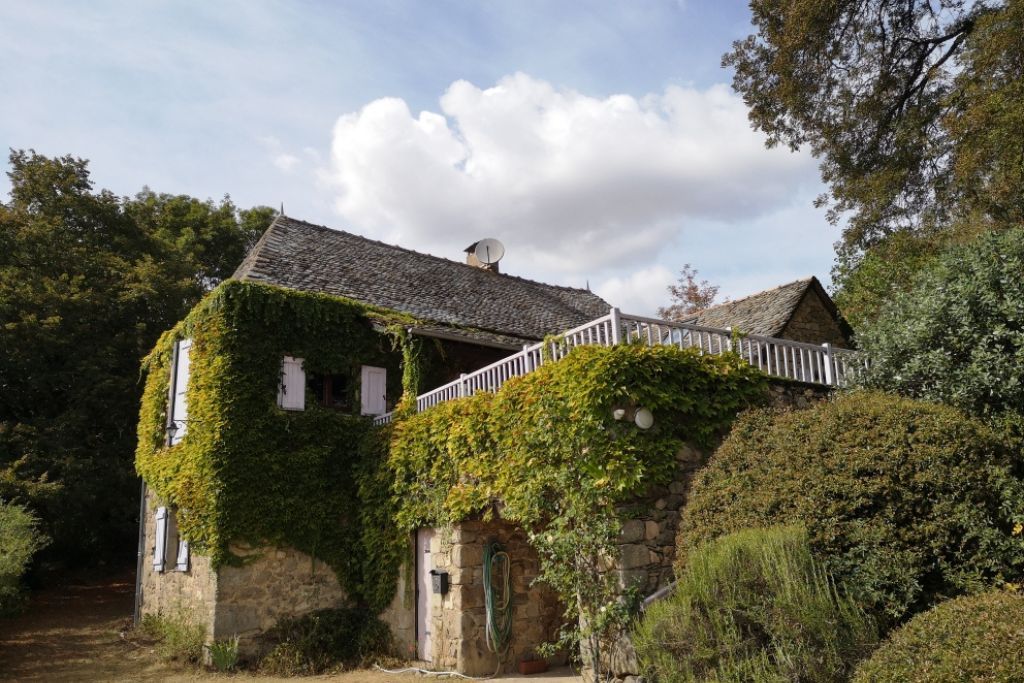 A stone house with ivy-covered walls and a white balcony.