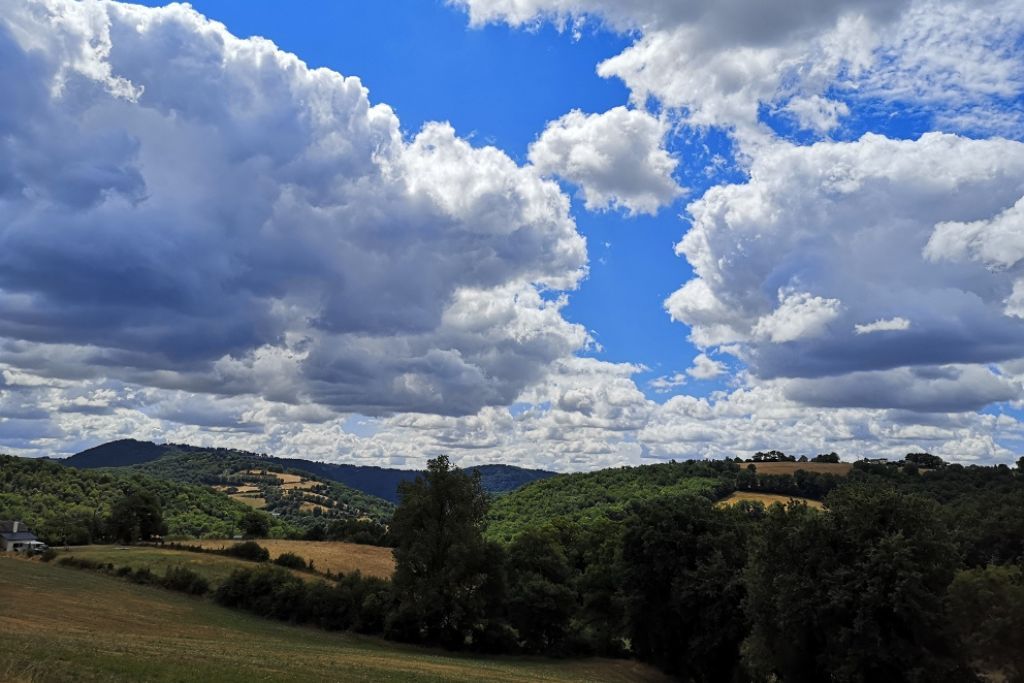 A landscape with rolling hills, a clear sky, and scattered clouds.