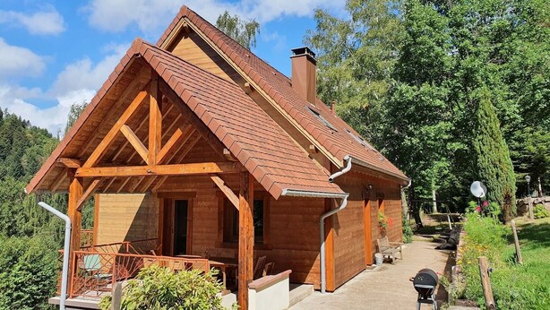 A wooden cabin with a pitched roof, a porch with seating, and a garden area. - Chalet *** surrounded by nature in the heart of Alsace Calm, comfort and authenticity (Fouchy)