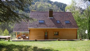 A wooden cabin with a tiled roof, a small porch, and a view of a forested hillside. - Chalet *** surrounded by nature in the heart of Alsace Calm, comfort and authenticity (Fouchy)