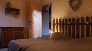 A bedroom with a wooden bed, a wooden dresser, a wooden door, and a wooden fence with heart-shaped decorations. - Chalet *** surrounded by nature in the heart of Alsace Calm, comfort and authenticity (Fouchy)