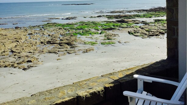 Uitzicht op het strand vanaf een overdekt terras met een witte bank.