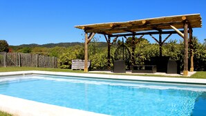 A rectangular swimming pool with a wooden pergola structure in the background.