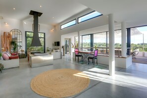 A spacious living room with a large window, a fireplace, and a dining area with a view.