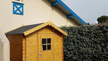 Situated near a building, this charming shed offers a single door and a window above.