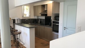 Een moderne keuken met een centraal eiland, inbouwapparatuur en een raam dat voor natuurlijk licht zorgt.