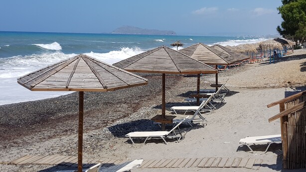 A beach with wooden umbrellas and lounge chairs. - House located in the center of an exceptional region to discover ! (Platanias Pirgos Spilorenou Crète)