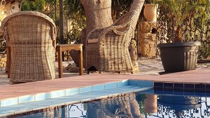 A pool with clear water reflecting surrounding trees and chairs. - House located in the center of an exceptional region to discover ! (Platanias Pirgos Spilorenou Crète)