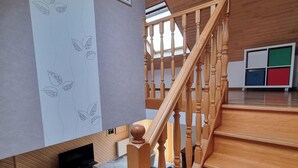 A modern interior with a wooden staircase, a flat-screen TV, and a sectional sofa.