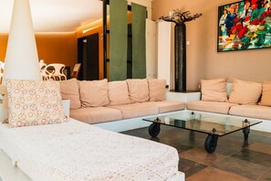 A modern living room with a sectional sofa, a glass coffee table, and a decorative tree sculpture.