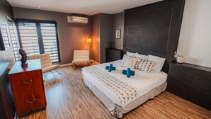A modern hotel room with a large bed, a wooden dresser, a chair, and a desk.