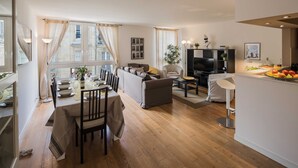 Un salon moderne comprenant un coin repas, un canapé, un téléviseur et un comptoir de cuisine avec des fruits.