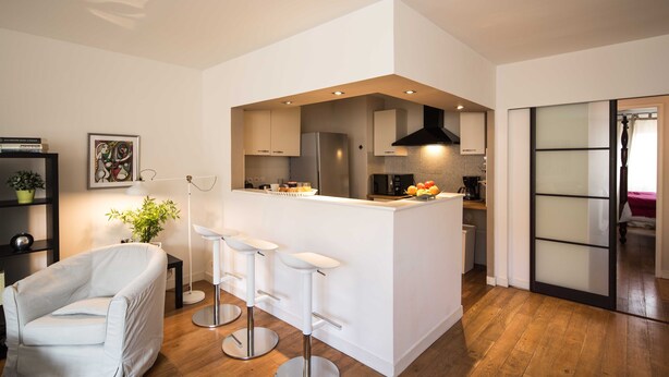 Une cuisine moderne dotée d’un îlot central, de tabourets de bar et d’un coin repas.