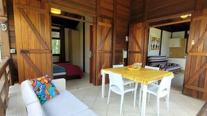 A wooden interior with a sofa, dining table, and chairs. - BUNGALOWS "Coco" typical Creole with all comforts, feet in the water  (DESHAIES)