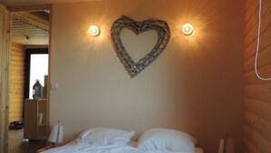Una camera da letto con un letto grande, una decorazione a forma di cuore sulla parete e due luci fissate al muro.