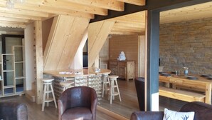 Un interno in legno con zona pranzo, un bar e un'area salotto con una poltrona in pelle e un divano.