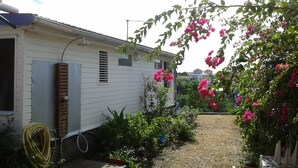 A mobile home with a garden area, a hose, and a wooden door.