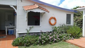 A house with a tiled roof, a window with a red curtain, and a life preserver hanging on the wall.