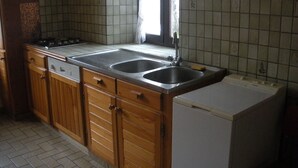 A kitchen with wooden cabinets, a double sink, and a built-in dishwasher. - Accommodation 4 people garden, quiet, GERARDMER FREE WIFI (Gérardmer)