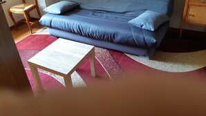 A room with a blue sofa, a wooden chair, a small wooden table, and a red and white rug. - Accommodation 4 people garden, quiet, GERARDMER FREE WIFI (Gérardmer)