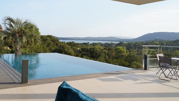 Ein moderner Poolbereich im Freien mit Blick auf das Meer und die Hügel.