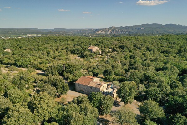 A stone building surrounded by dense forest with a clear view of distant mountains.