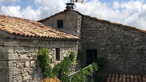 Een gebouw van steen met een pannendak, een jacuzzi op de voorgrond en een heldere lucht.