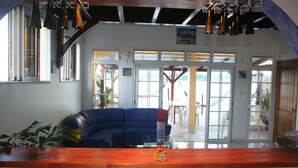 A spacious living area with a blue sofa, a wooden coffee table, and a view through large glass doors to an outdoor deck. - Apartment of 190 m2 above the water (La Trinité)