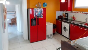 A compact kitchen with red cabinets, a washing machine, and a small sink. - Apartment of 190 m2 above the water (La Trinité)