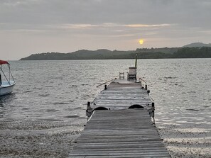 A wooden pier extending into calm water with a boat docked on the left. - Apartment of 190 m2 above the water (La Trinité)