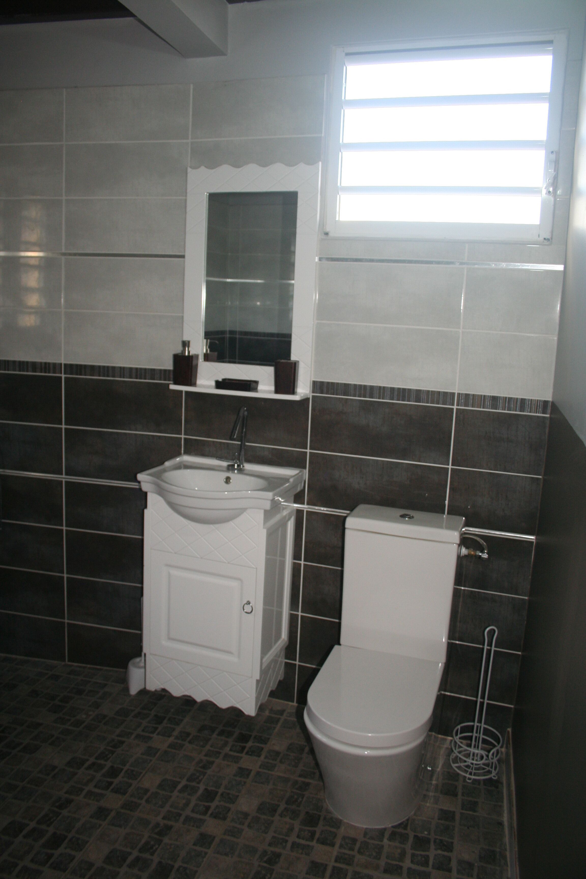 Un bagno con il water, un lavandino e uno specchio.