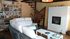 A living room with a sectional sofa, a white coffee table, a bookshelf, and a staircase.