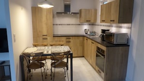 A compact kitchen with wooden cabinets, a microwave, and a dining table with chairs.