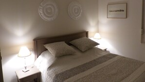 A bedroom with a bed, two bedside lamps, and a framed picture on the wall.