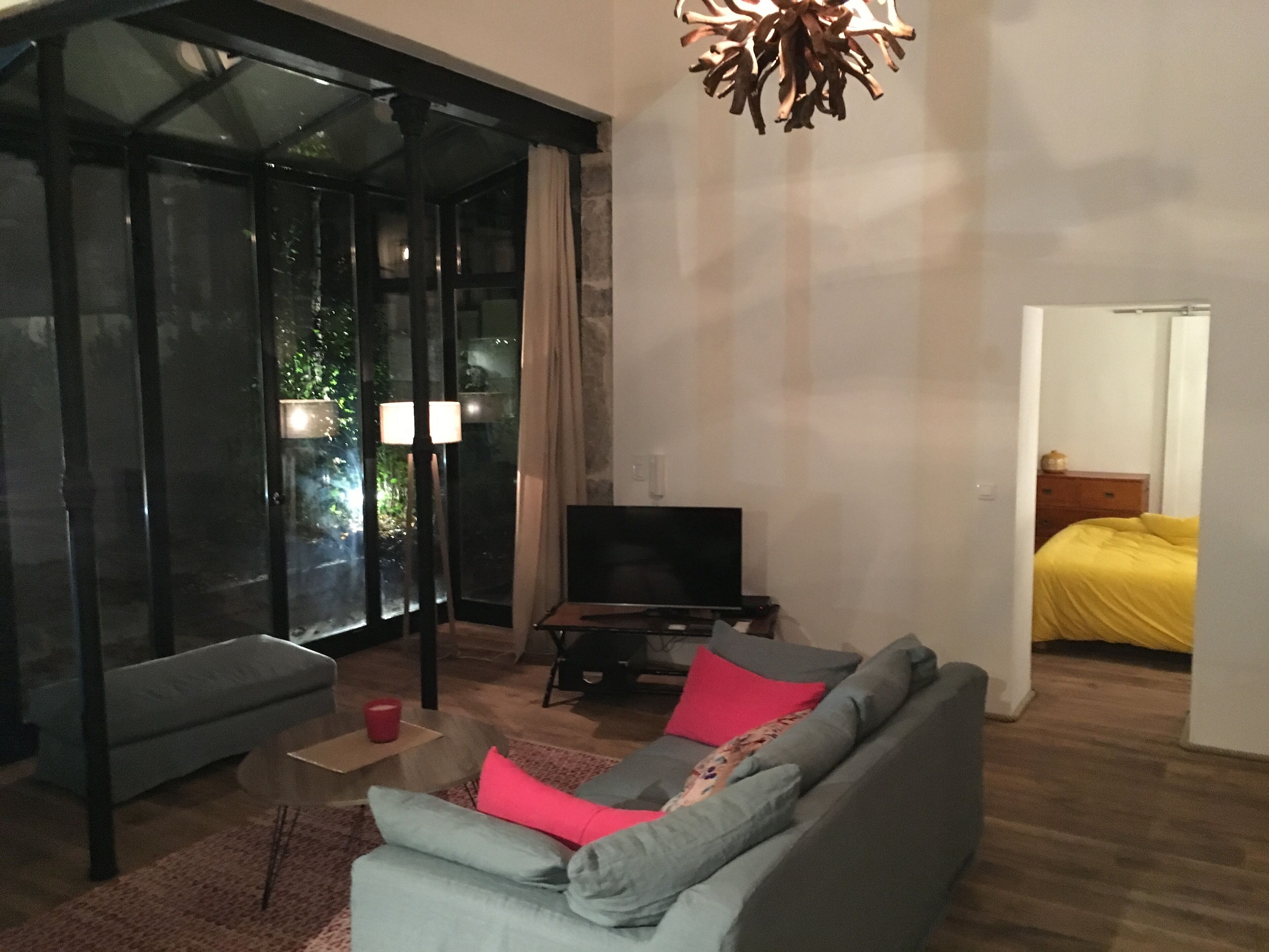 A living room with a sofa, TV, and a glass door leading to a balcony.