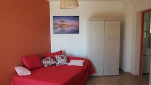 Une chambre à coucher comprenant un lit, une armoire, un luminaire suspendu et un tableau accroché au mur.