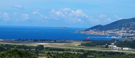 A pool with clear blue water, a view of a coastal city, and a distant mountain range.