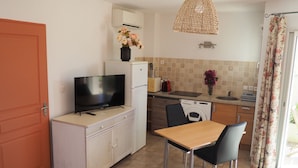 Une cuisine compacte équipée d’un téléviseur, d’un lave-linge et d’un coin repas avec des chaises.