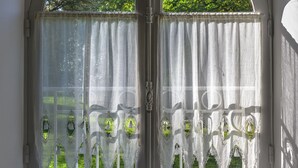 Een kamer met een groot rondboogvenster, witte gordijnen en decoratieve kantdetails.