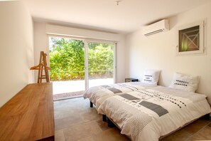 A bedroom with a bed, a desk, and a view of greenery through a sliding door. - 10 minutes walk from the beach of Saint Cyprien, by trails. (Zonza)