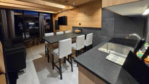 Une cuisine moderne avec un plan de travail noir, un évier en acier inoxydable et des armoires en bois.