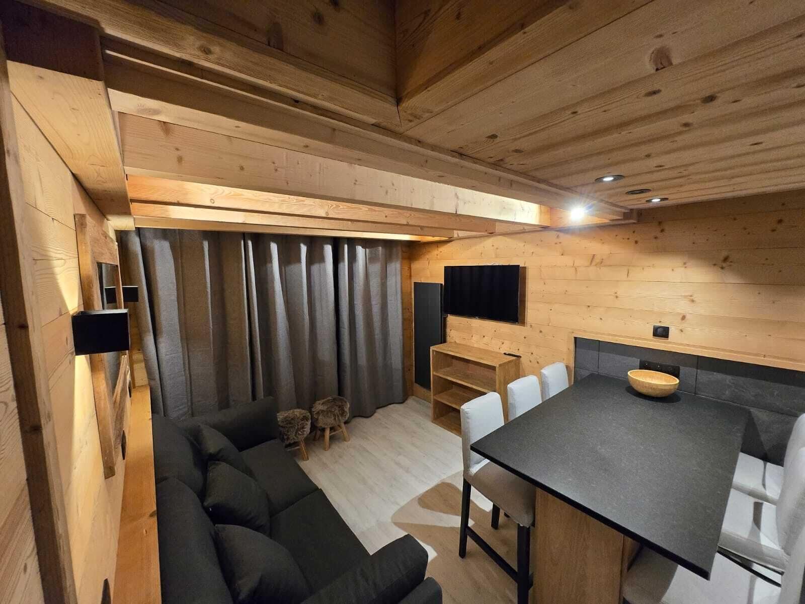 A cozy, wooden interior with a sofa, dining table, and chairs.
