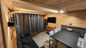 Un intérieur chaleureux, avec des éléments en bois, comprenant un canapé, une table à manger et des chaises.