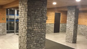 Un hall d’entrée spacieux, avec des piliers en pierre, un sol carrelé et un plafond en bois.